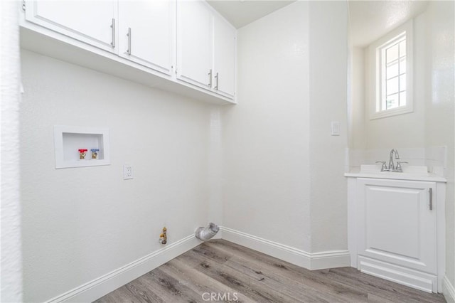 laundry area featuring cabinets, hookup for a washing machine, sink, and light hardwood / wood-style floors