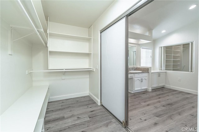 walk in closet with sink and light wood-type flooring