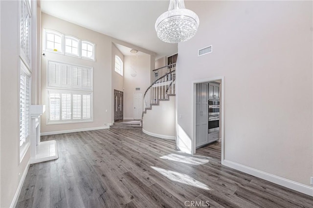 foyer featuring hardwood / wood-style flooring, a towering ceiling, and a notable chandelier