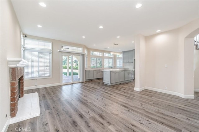 unfurnished living room with a brick fireplace, sink, and light hardwood / wood-style flooring