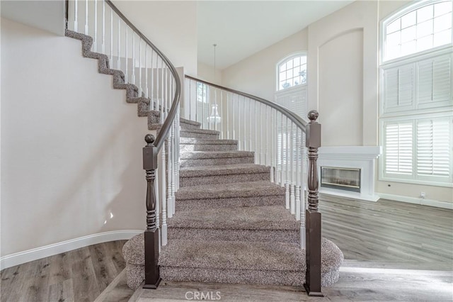 stairs with a towering ceiling and wood-type flooring