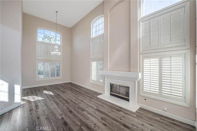 unfurnished living room featuring dark hardwood / wood-style flooring, a notable chandelier, and plenty of natural light