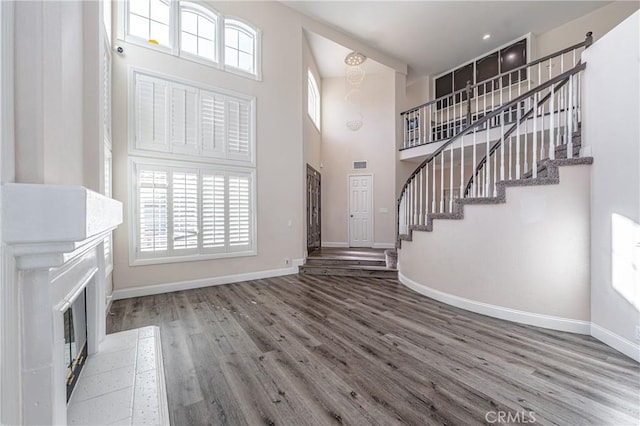 unfurnished living room with hardwood / wood-style flooring and a towering ceiling