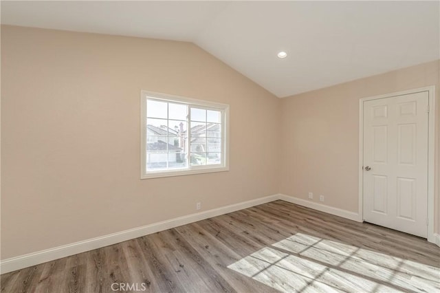 spare room with light hardwood / wood-style floors and vaulted ceiling