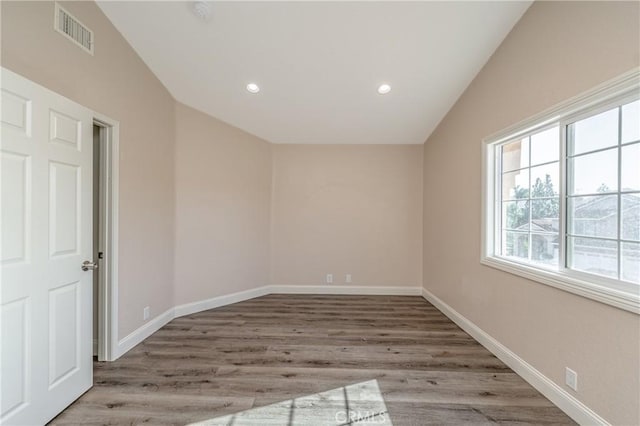 spare room with wood-type flooring and lofted ceiling