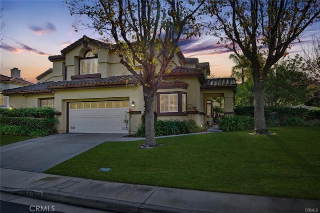 mediterranean / spanish-style house with a garage and a yard