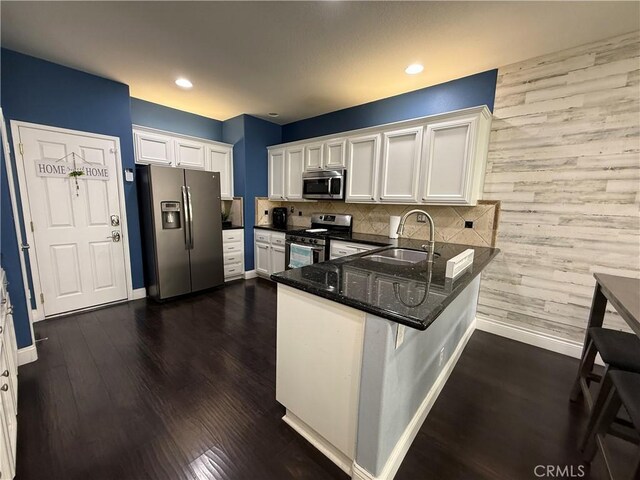 kitchen with appliances with stainless steel finishes, kitchen peninsula, sink, and white cabinets