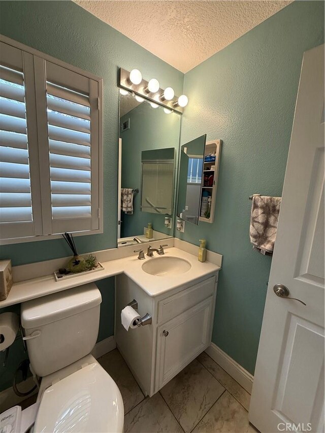 bathroom with vanity, toilet, tile patterned flooring, and a textured ceiling