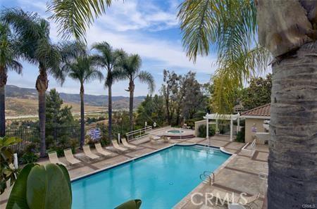 view of swimming pool with a hot tub, a mountain view, and a patio area