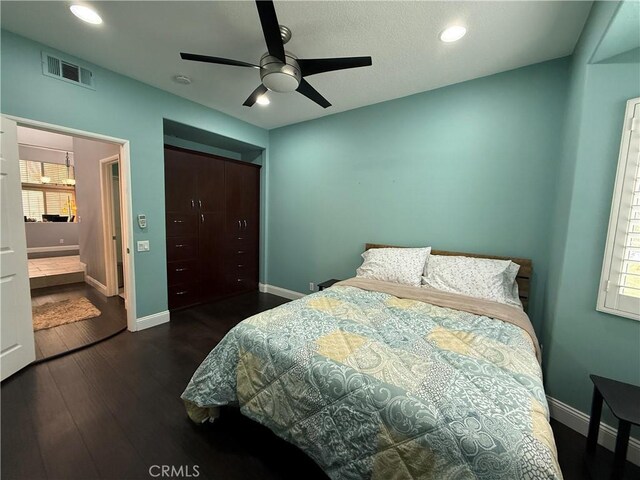 bedroom with dark wood-type flooring, ceiling fan, and a closet