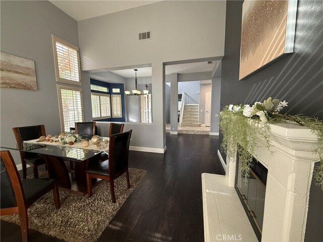 dining area featuring dark hardwood / wood-style flooring, a towering ceiling, and a chandelier