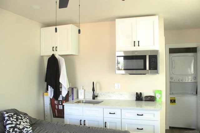 kitchen featuring sink, stacked washer and clothes dryer, and white cabinets