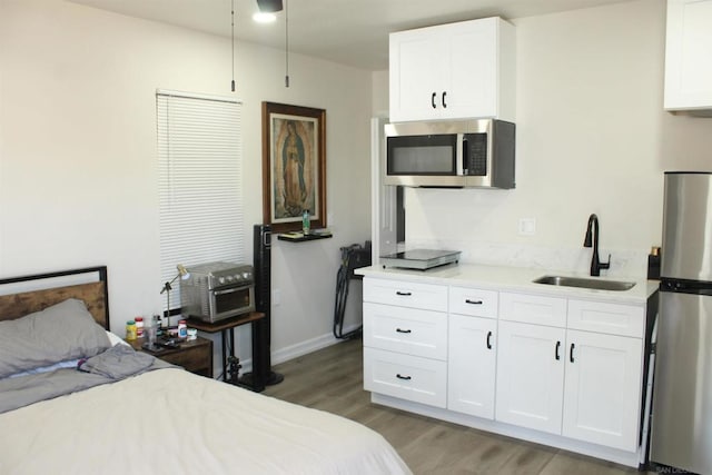 bedroom featuring hardwood / wood-style flooring, sink, and stainless steel refrigerator