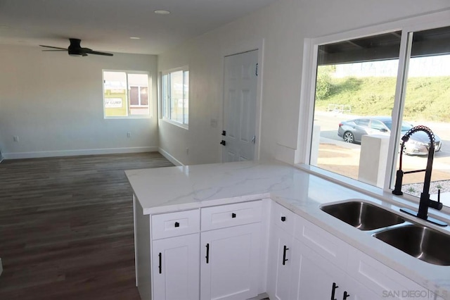 kitchen with dark wood-type flooring, sink, ceiling fan, light stone countertops, and white cabinets