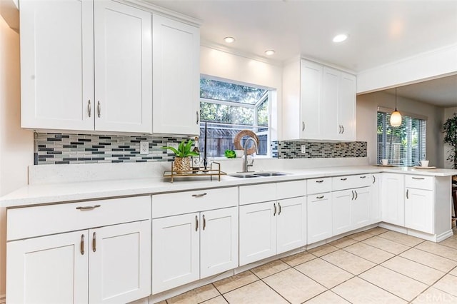 kitchen featuring light tile patterned floors, a sink, white cabinetry, light countertops, and decorative light fixtures