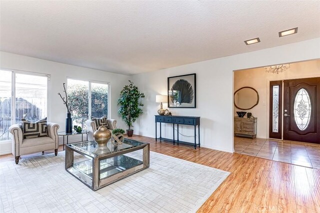 living room featuring a textured ceiling, baseboards, and wood finished floors