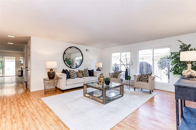 living room featuring plenty of natural light, light wood-style flooring, and baseboards