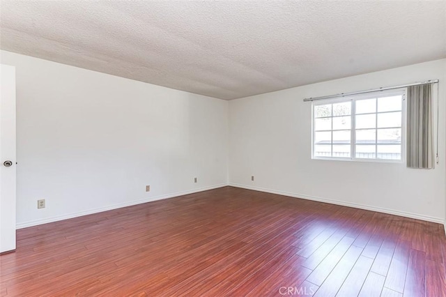 unfurnished room with a textured ceiling, wood finished floors, and baseboards