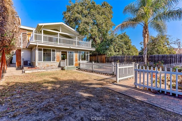 view of front of house with a balcony, a fenced backyard, and cooling unit