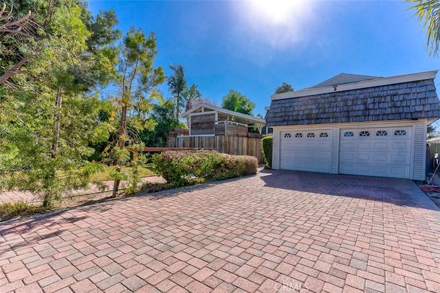 garage featuring fence and decorative driveway