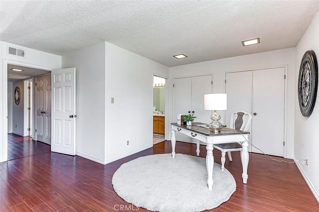 office space featuring visible vents, dark wood finished floors, a textured ceiling, and baseboards