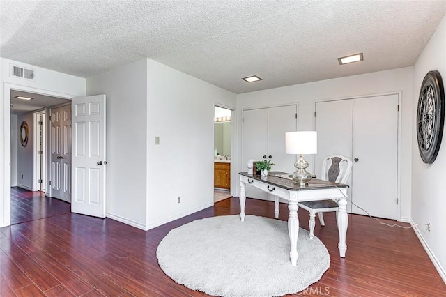 home office featuring baseboards, visible vents, a textured ceiling, and wood finished floors