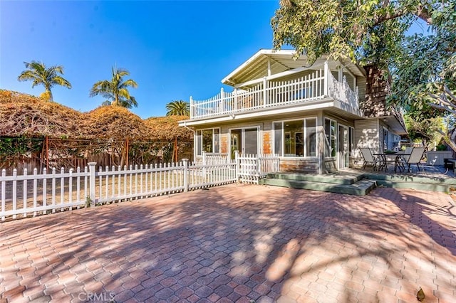 front of property with a patio area, fence, and a balcony