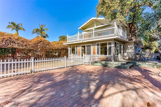 view of front of property featuring fence, a patio, and a balcony