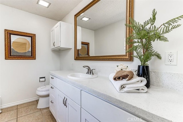 bathroom featuring a textured ceiling, toilet, vanity, baseboards, and tile patterned floors