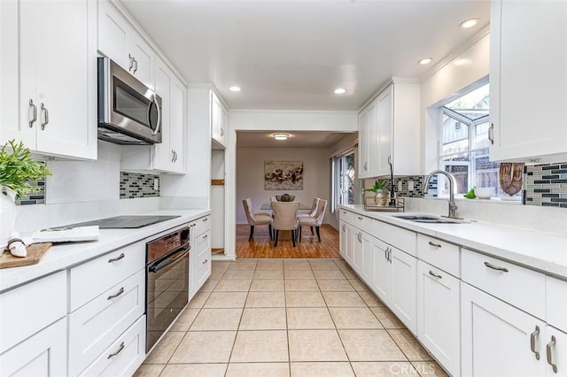 kitchen featuring light countertops, stainless steel microwave, oven, and white cabinets