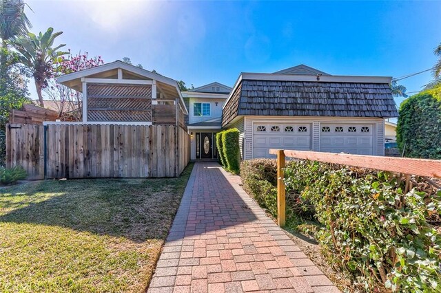 view of front of house featuring a garage, fence, mansard roof, and a front yard