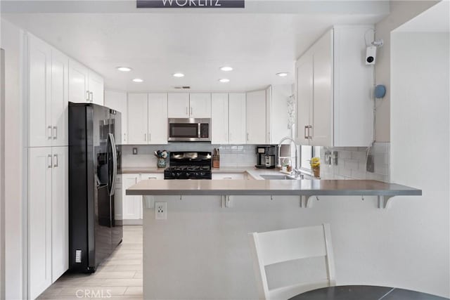 kitchen with stainless steel appliances, kitchen peninsula, and white cabinets