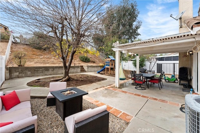 view of patio with a playground and an outdoor living space with a fire pit