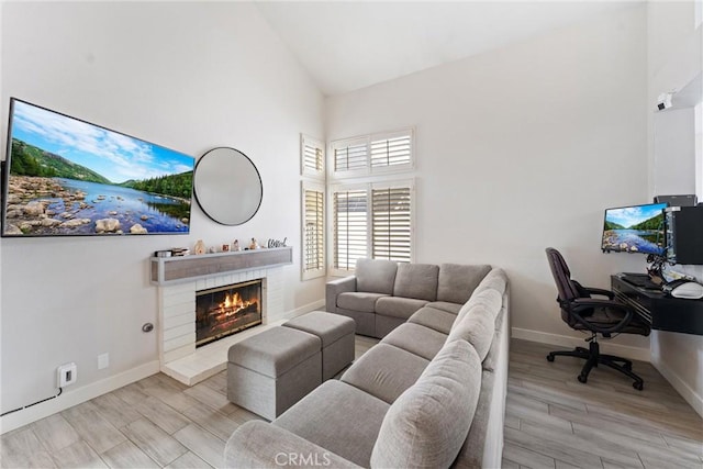 living room with high vaulted ceiling, light hardwood / wood-style floors, and a brick fireplace