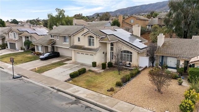 view of front of house featuring a garage, a mountain view, a front yard, and solar panels