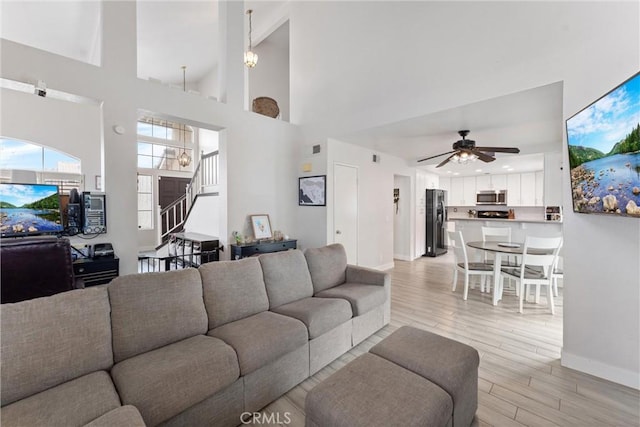 living room featuring high vaulted ceiling, light hardwood / wood-style floors, and ceiling fan