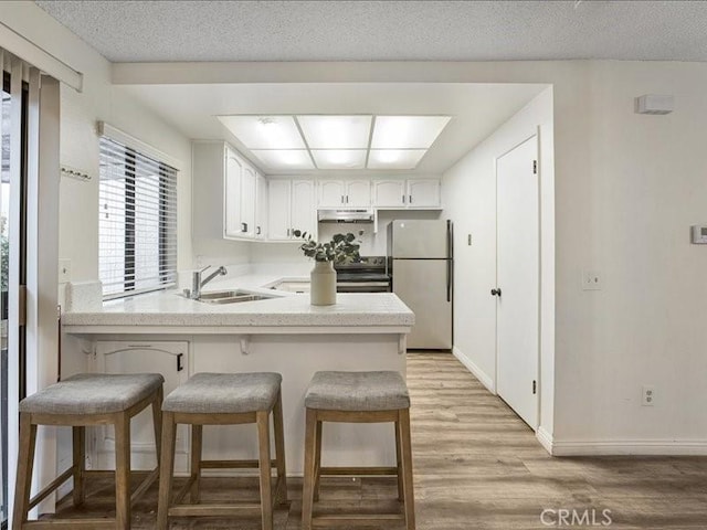 kitchen featuring a breakfast bar, sink, refrigerator, and kitchen peninsula