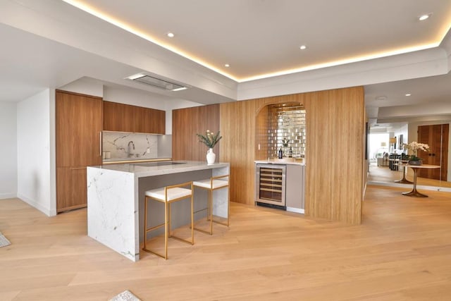 kitchen with wine cooler, light hardwood / wood-style flooring, a breakfast bar area, and a center island