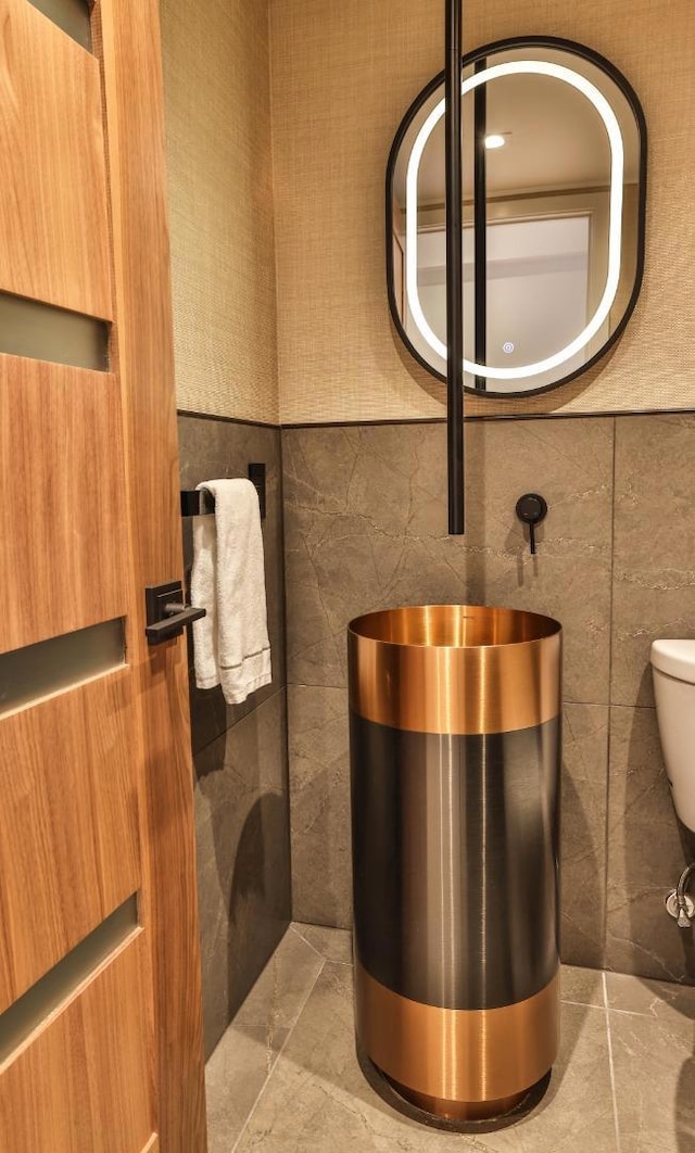 bathroom with toilet and tile walls