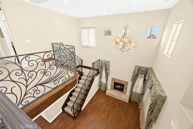 stairs featuring wood-type flooring, a premium fireplace, and a chandelier