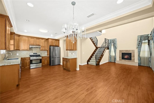 kitchen featuring sink, decorative light fixtures, appliances with stainless steel finishes, a premium fireplace, and backsplash