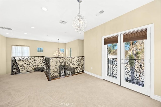 corridor featuring light carpet, a notable chandelier, and french doors