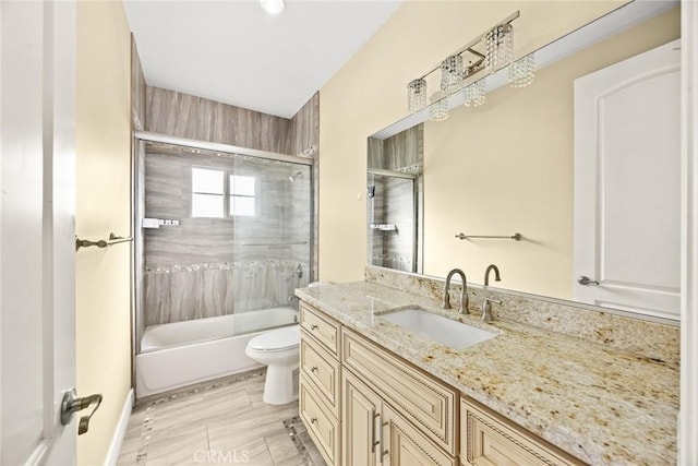 full bathroom featuring vanity, enclosed tub / shower combo, and toilet