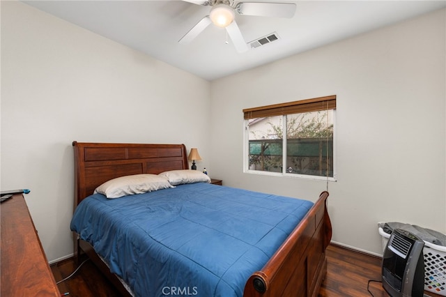 bedroom with heating unit, dark hardwood / wood-style floors, and ceiling fan