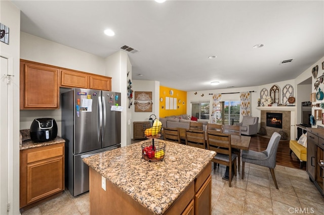 kitchen featuring stainless steel fridge, light stone countertops, and a kitchen island