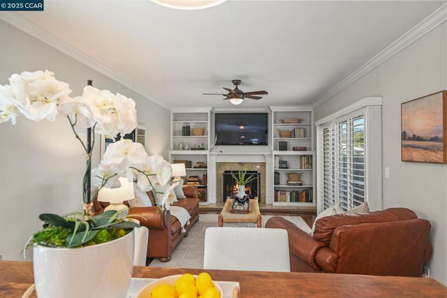 living room featuring a fireplace, ornamental molding, built in features, and ceiling fan