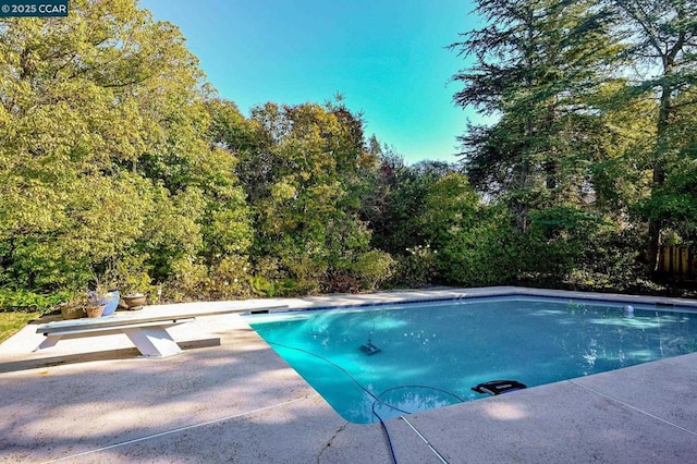 view of pool with a diving board and a patio