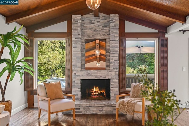 living area with wood ceiling, hardwood / wood-style flooring, a stone fireplace, and lofted ceiling with beams