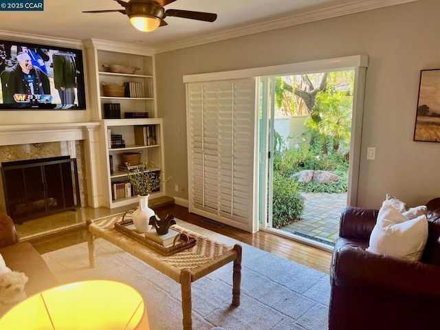 living room featuring crown molding, light hardwood / wood-style floors, and a tile fireplace