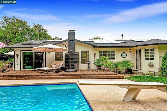 rear view of house with a pool side deck and solar panels